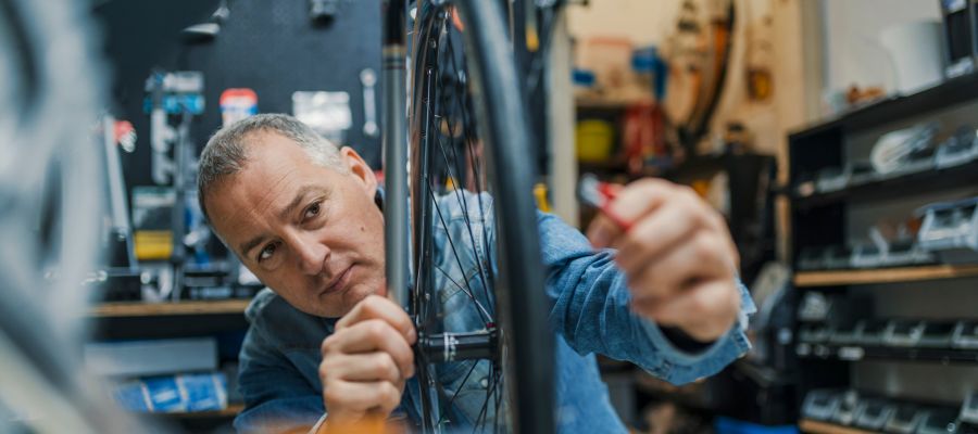 Ein älterer Mann repariert in einer Fahrradwerkstatt das Vorderrad eines Fahrrads