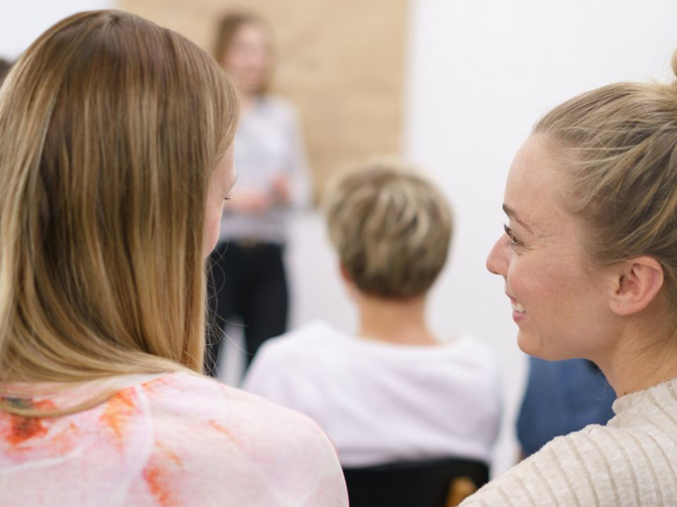 Zwei Frauen sitzen im Unterrichtsraum und sprechen miteinander