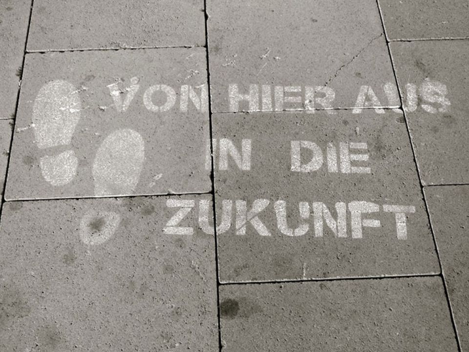 Bürgersteig mit den aufgesprühten Worten "Von hier aus in die Zukunft"