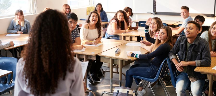 Eine Lehrerin steht im Klassenraum vor ihren Schüler:innen und unterrichtet sie